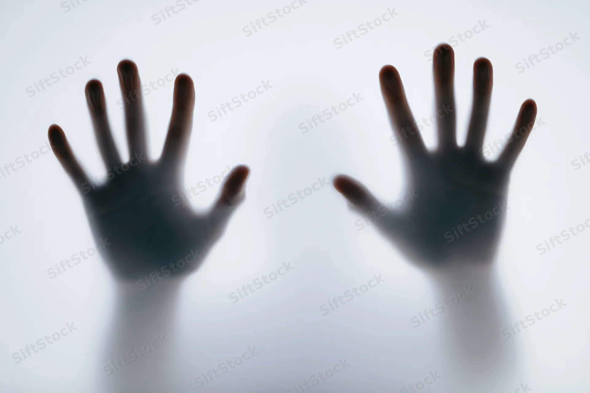 Two human hands pressing against a frosted translucent surface