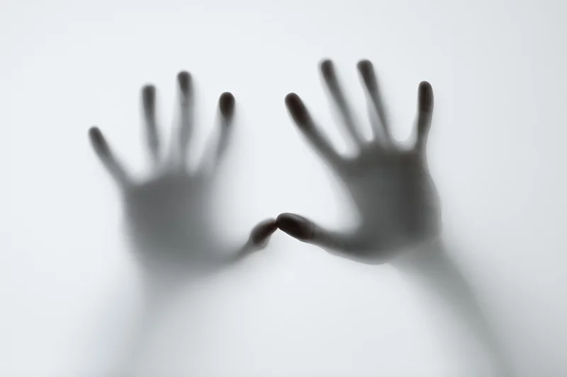 Two hands pressing against a frosted translucent surface