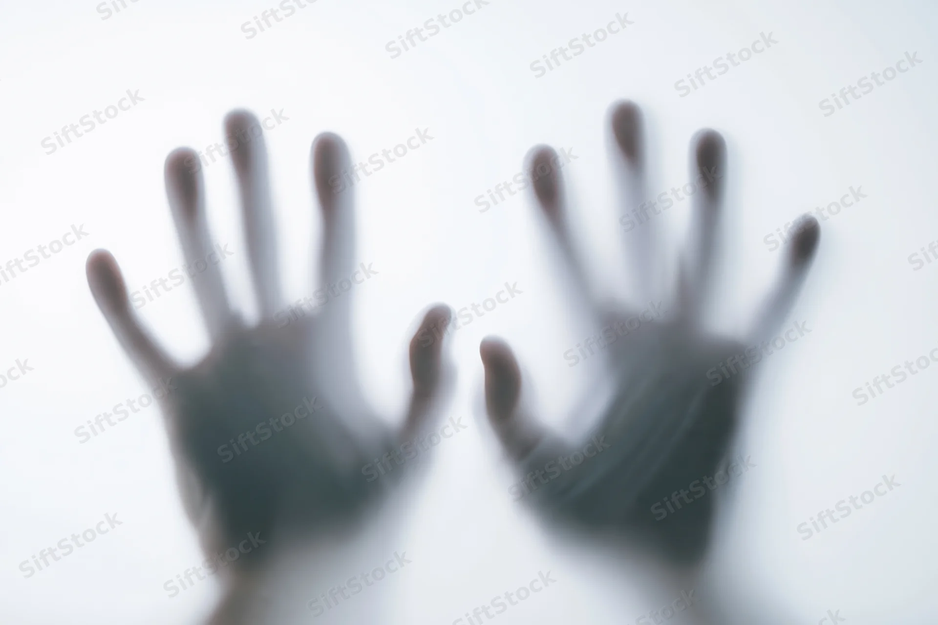 Two human hands pressing against a frosted translucent surface