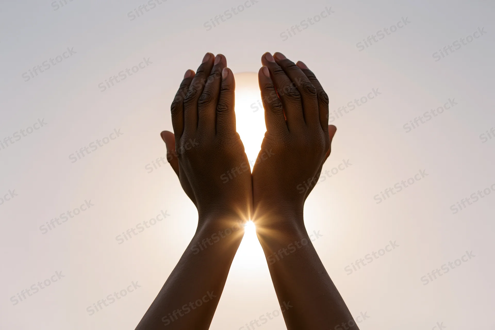 Hands raised upward cupping sunlight against a clear sky
