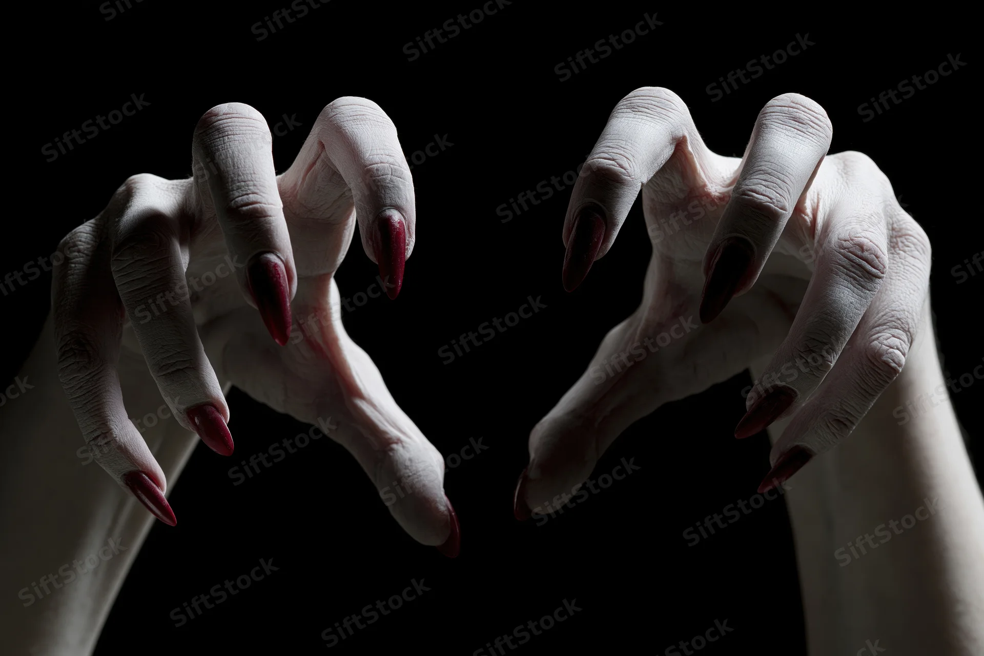 Pale clawed hands with red nails reaching forward from darkness
