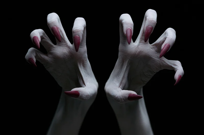 Pale grey clawed hands reaching forward from darkness