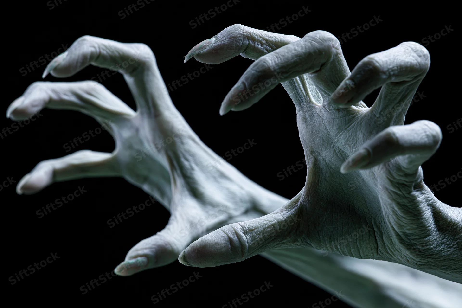 Pale grey contorted hands with long sharp nails reaching against black background