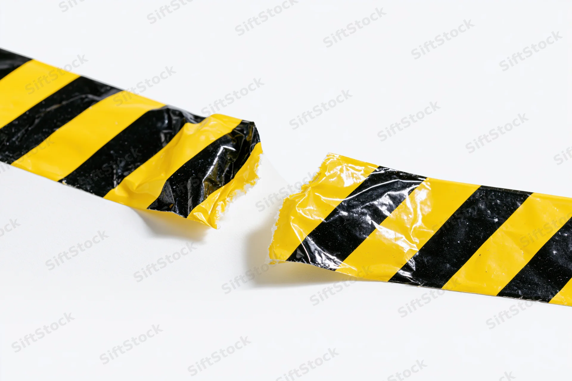 Torn pieces of yellow and black striped hazard tape on white background
