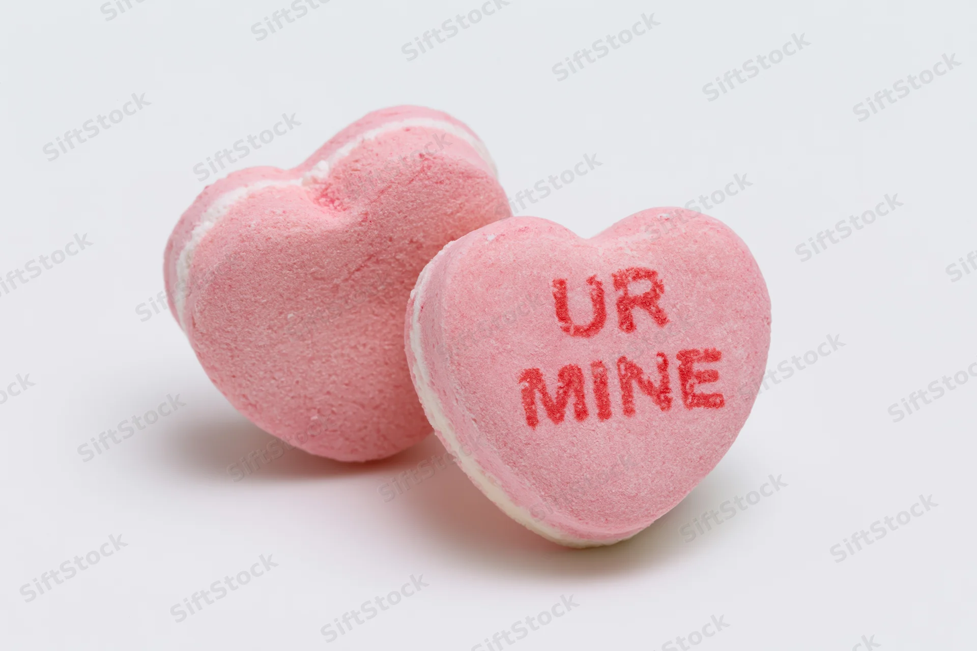 Two pink heart-shaped candies with text on white background