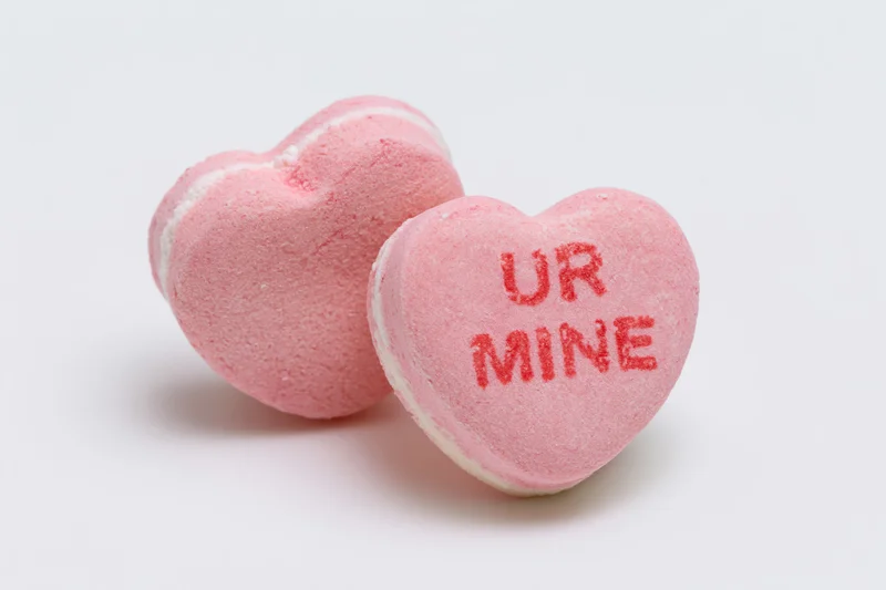Two pink heart-shaped candies with text on white background