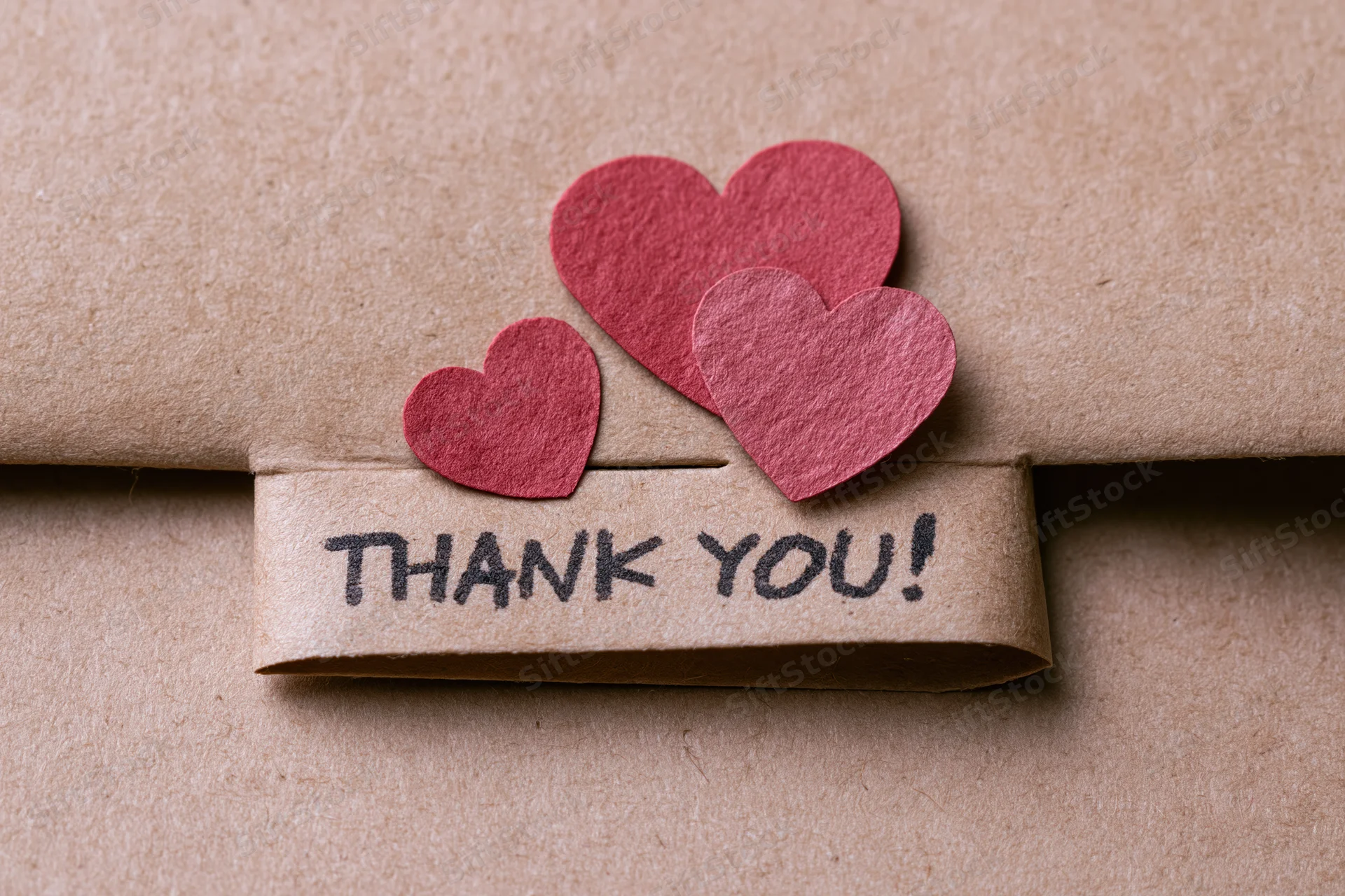 Brown paper-wrapped gift with red paper hearts and thank you tag