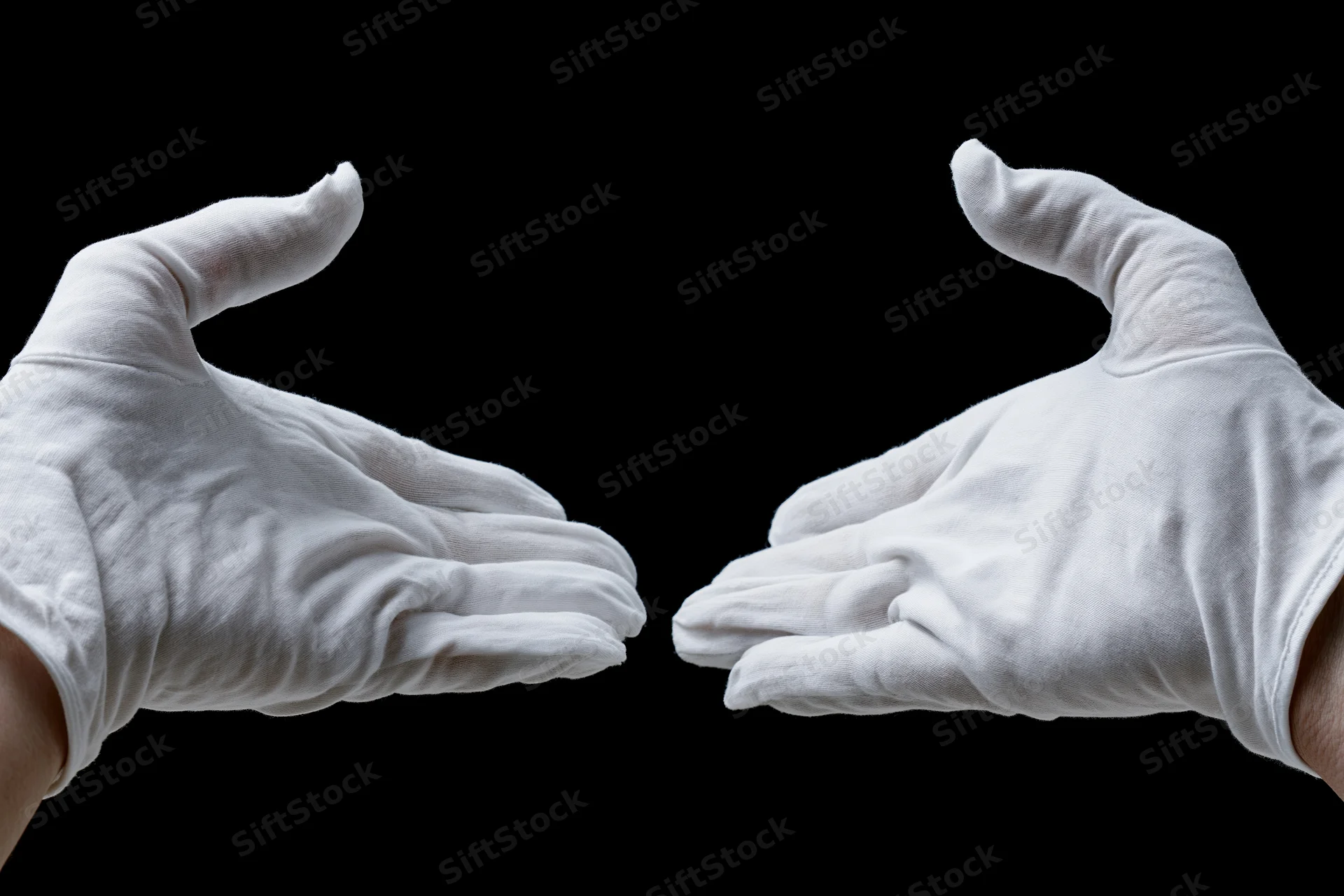 Two white-gloved hands reaching inward from opposite sides against black background