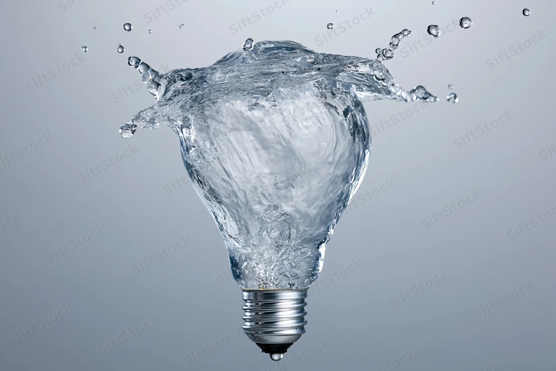 Water splashing in the shape of a light bulb frozen mid-motion against a gray background
