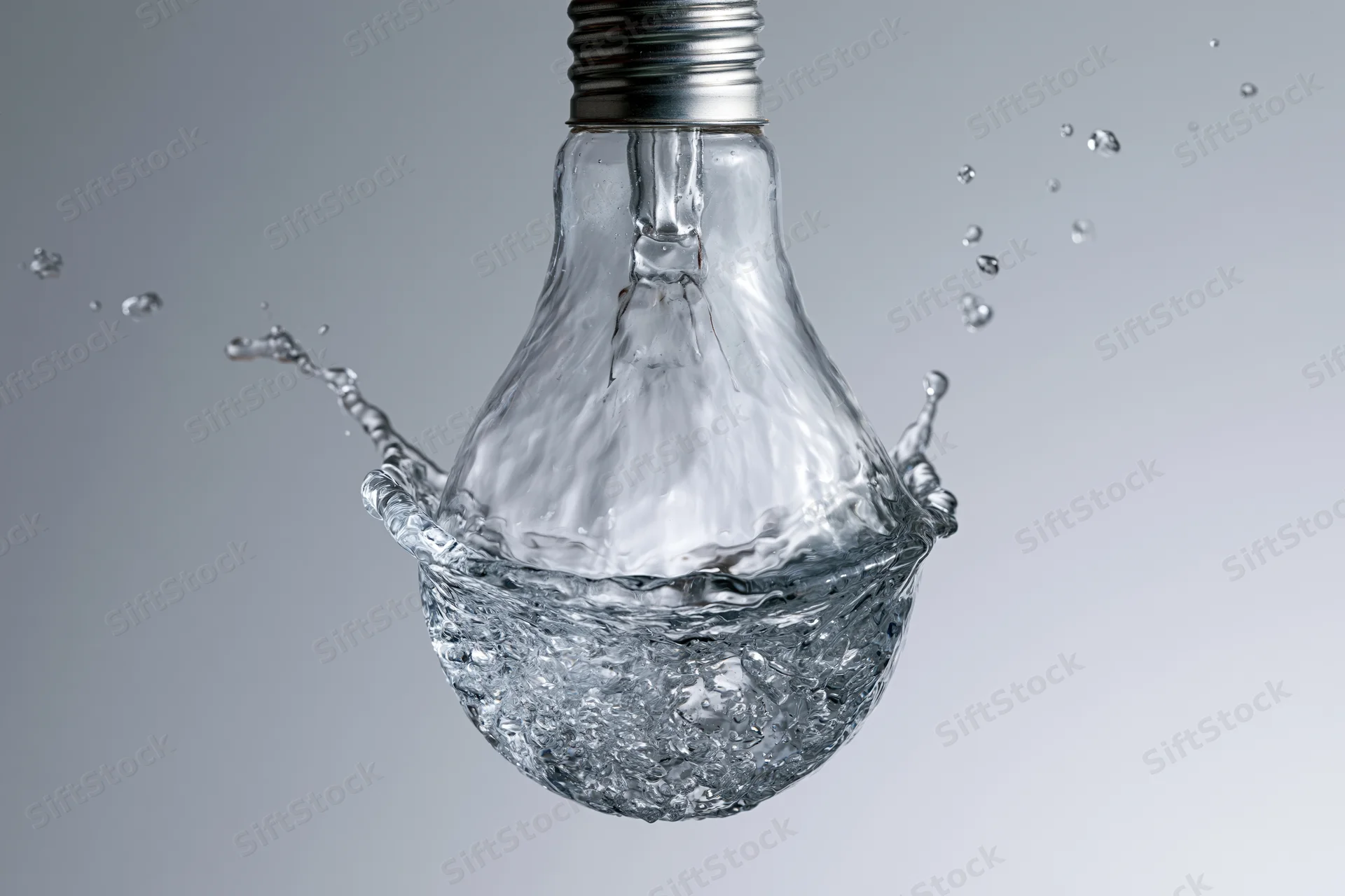Water splashing in the shape of a light bulb frozen midair against a gray background