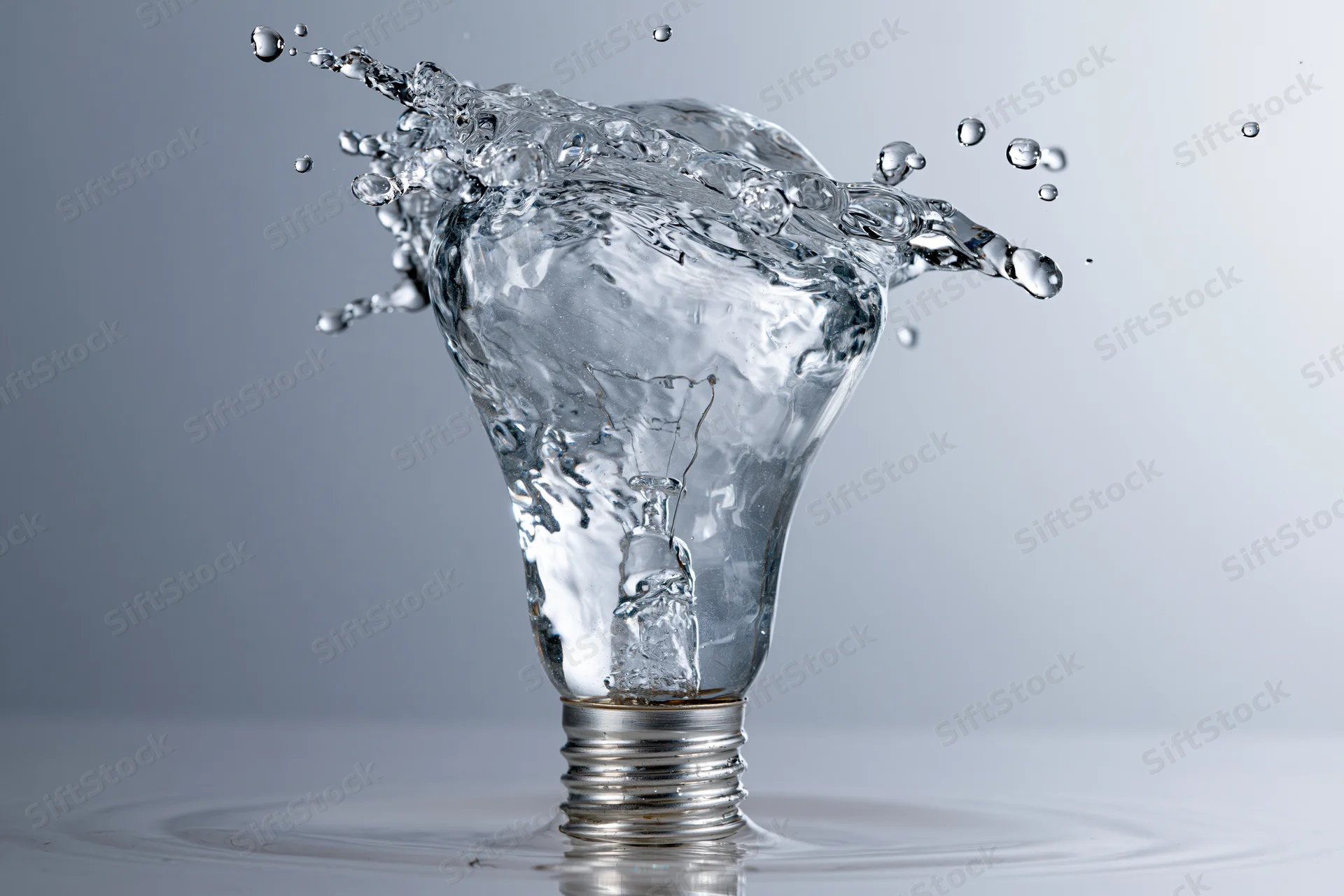 Water splashing in the shape of a light bulb frozen midair on a reflective surface