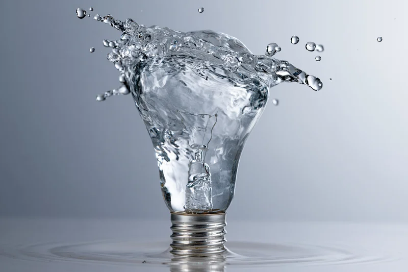 Water splashing in the shape of a light bulb frozen midair on a reflective surface