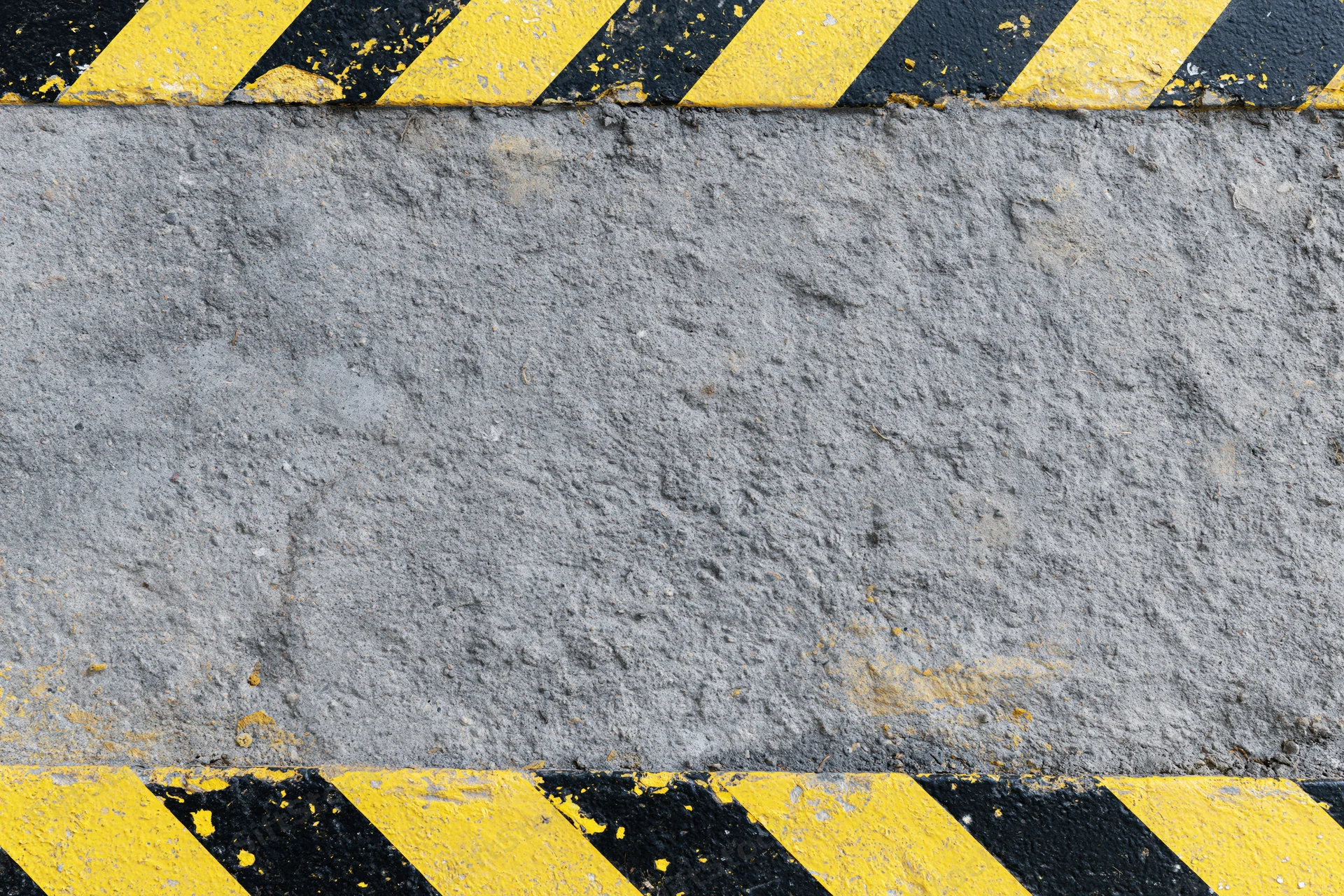 Weathered concrete pavement with diagonal yellow and black hazard stripes