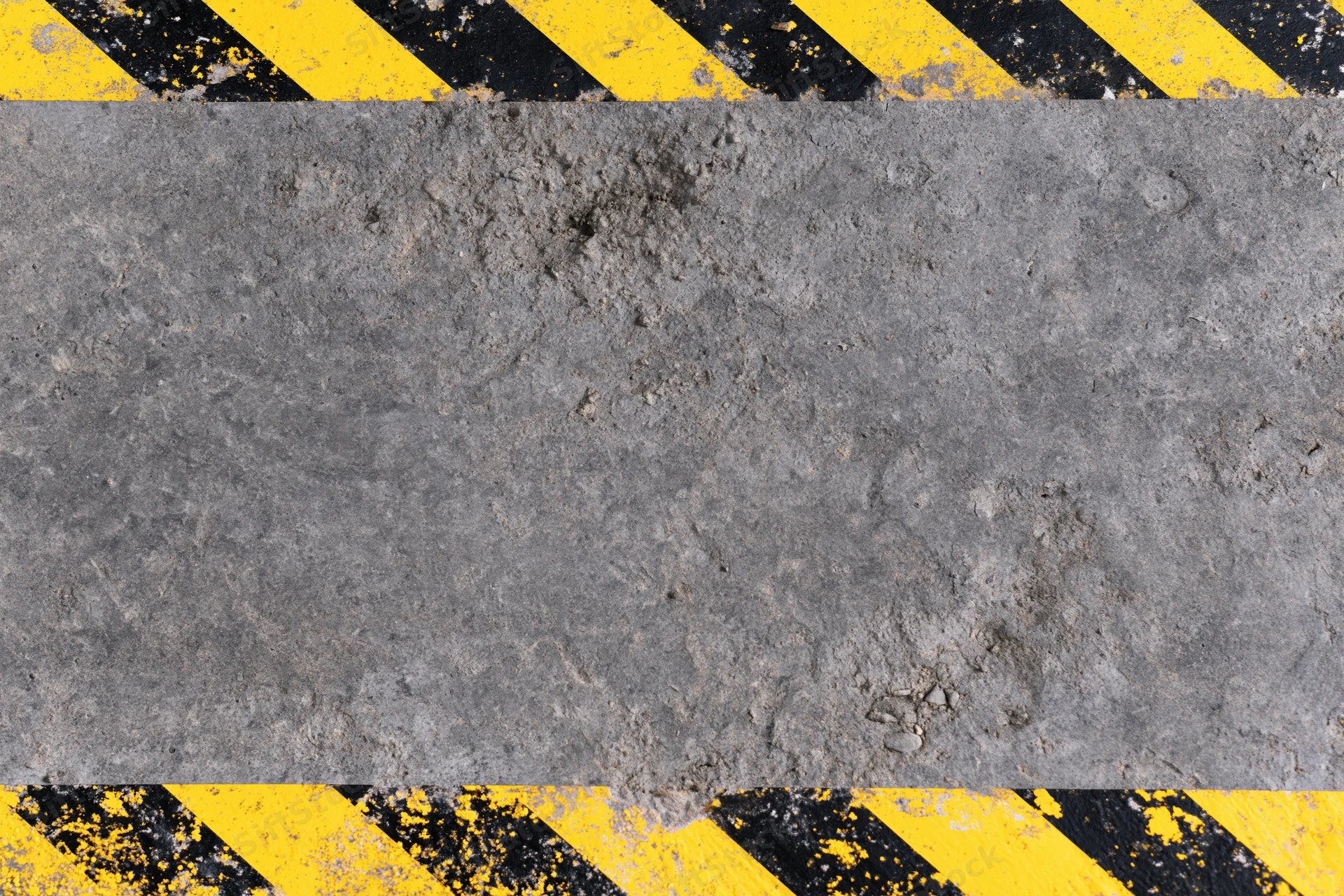 Weathered concrete surface with diagonal yellow and black hazard stripes