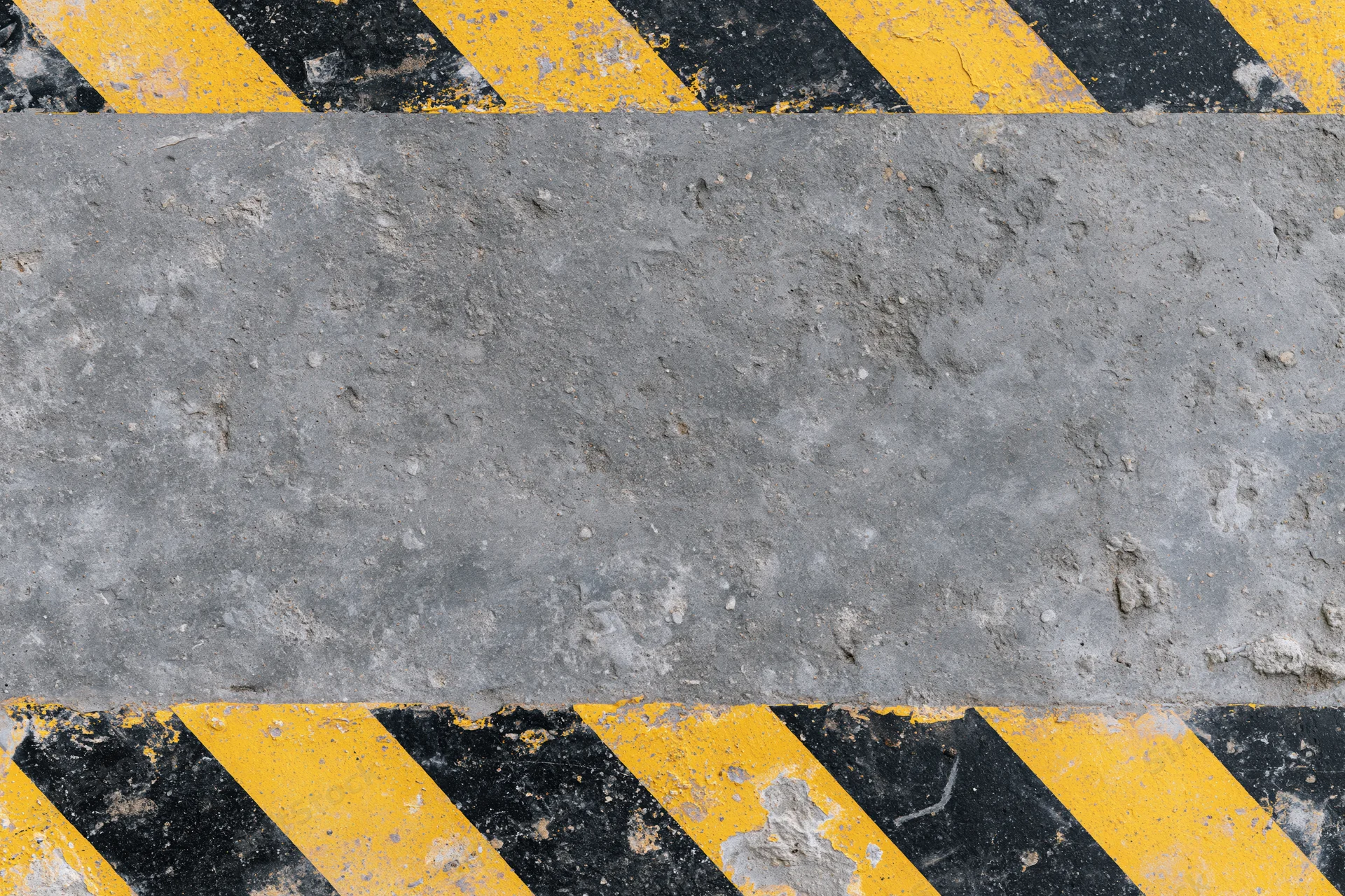 Weathered concrete surface with diagonal yellow and black hazard stripes