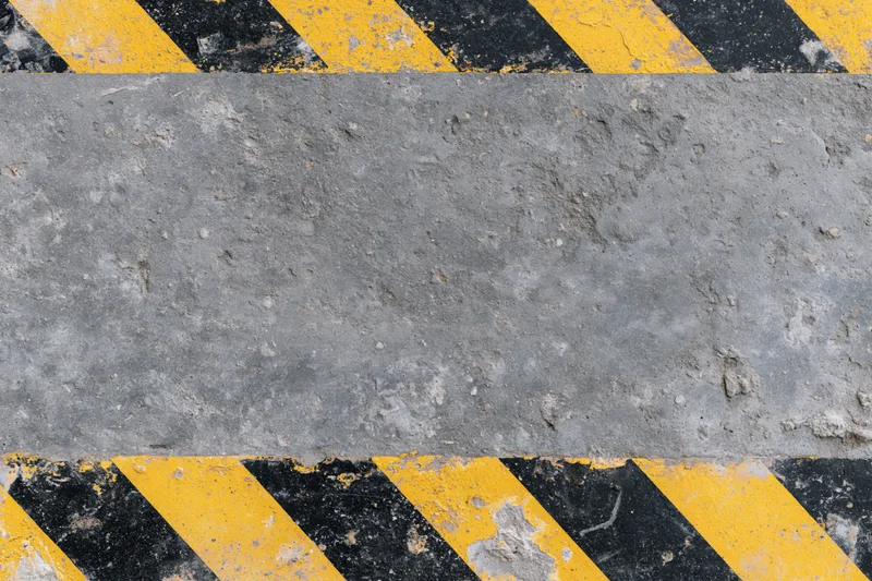 Weathered concrete surface with diagonal yellow and black hazard stripes