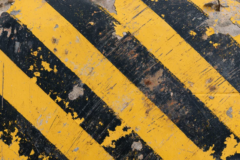 Weathered yellow and black diagonal stripes on an industrial floor surface
