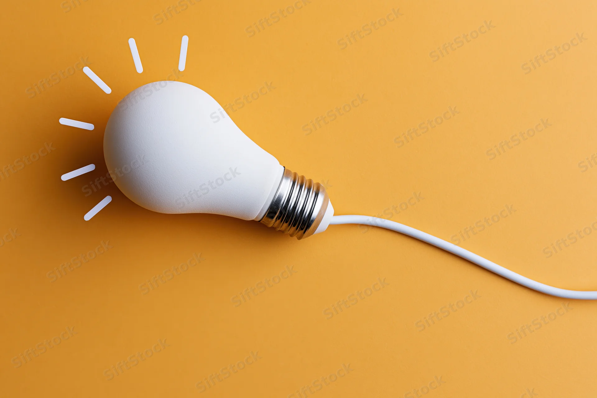 White led lightbulb lying flat with cord on orange surface