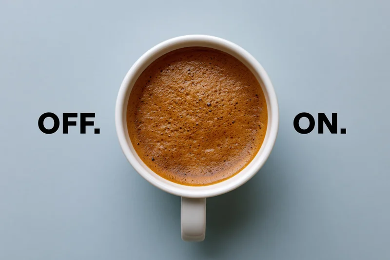 White ceramic coffee mug filled with espresso crema viewed from above on a light blue surface with the words off and on on either side