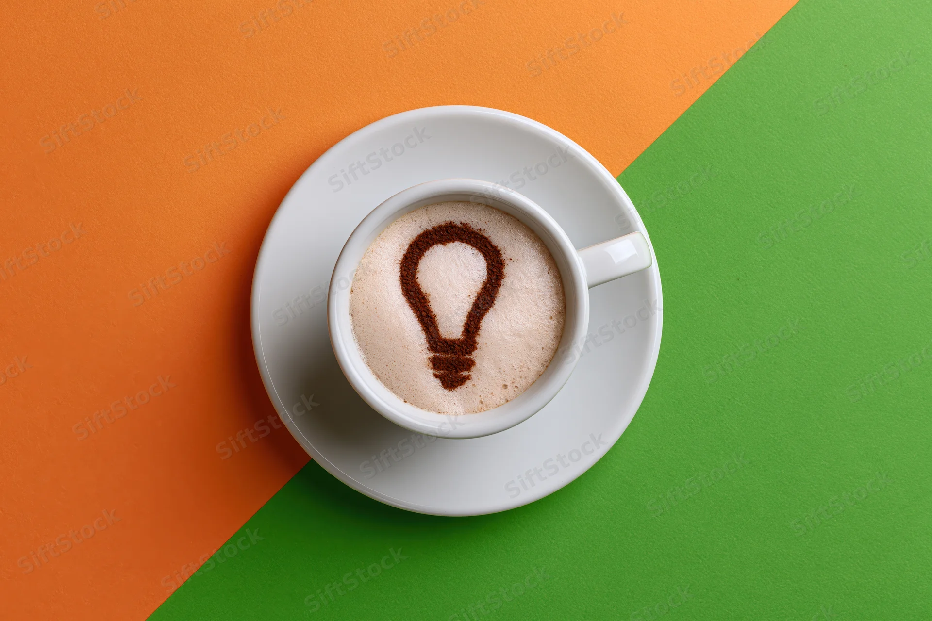 White ceramic espresso cup with cinnamon lightbulb design in foam on orange and green background