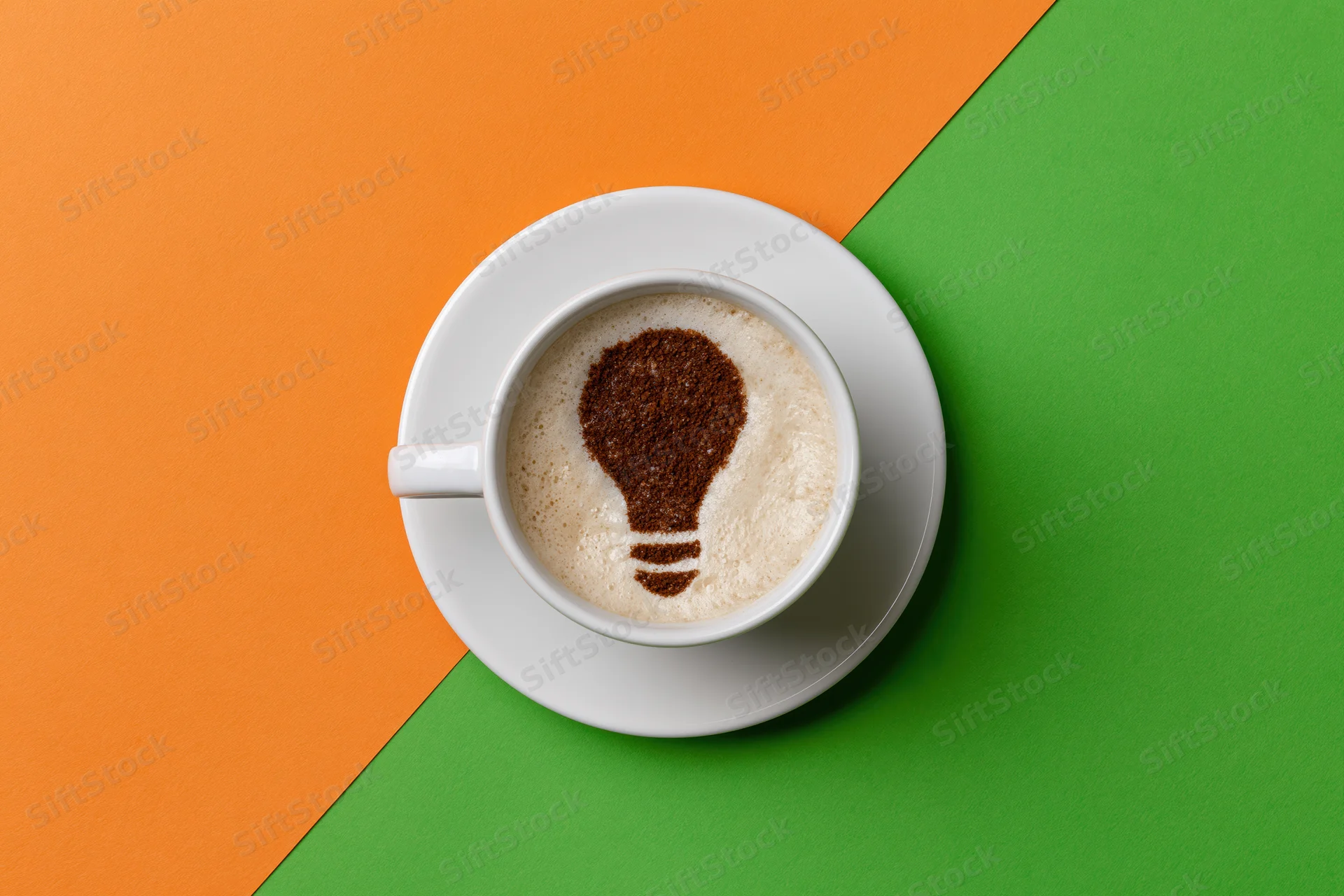 White ceramic espresso cup with cinnamon lightbulb design in foam on orange and green colorblock surface