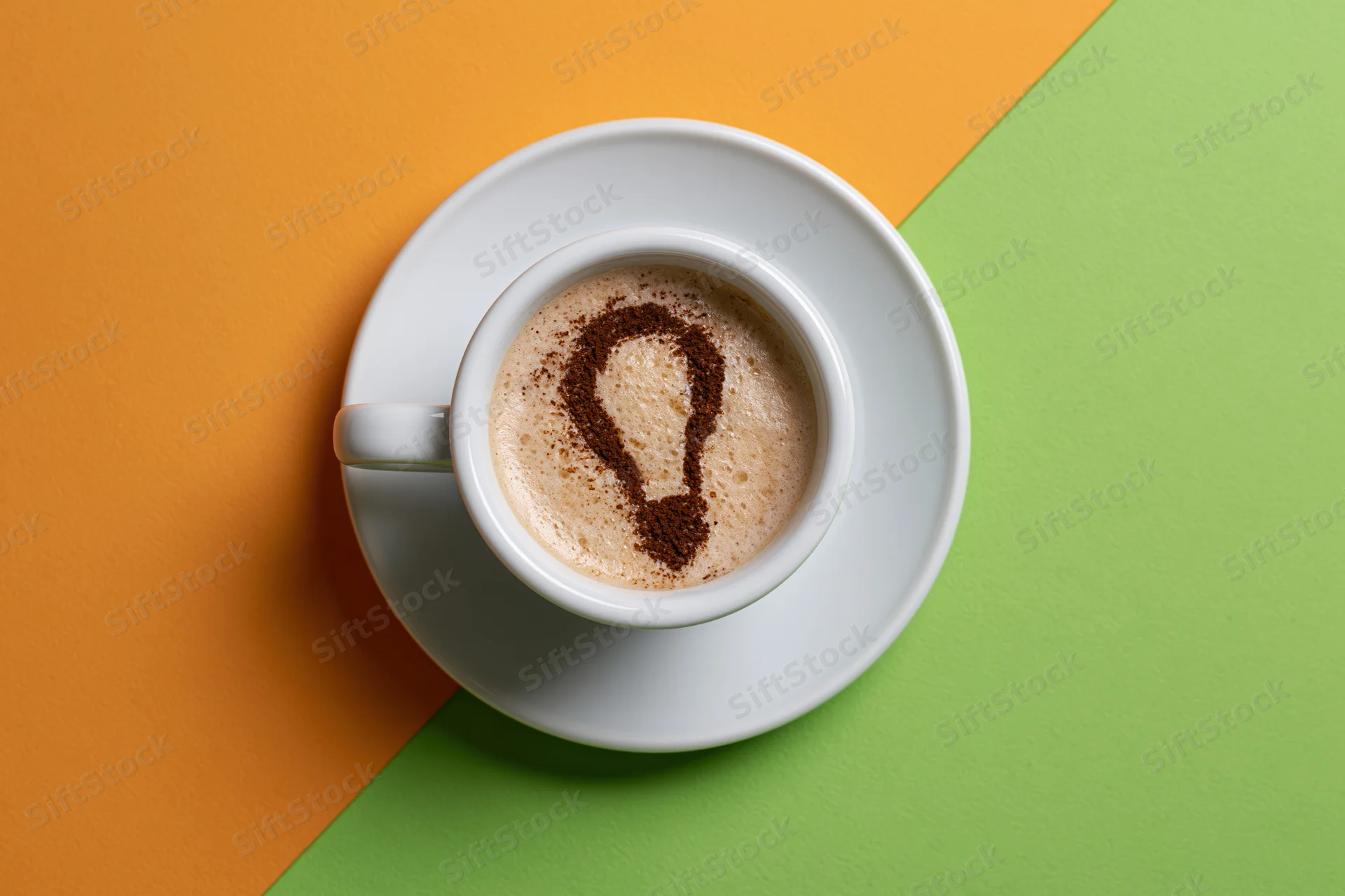 White ceramic espresso cup with cocoa-dusted lightbulb shape in foam on orange and green background