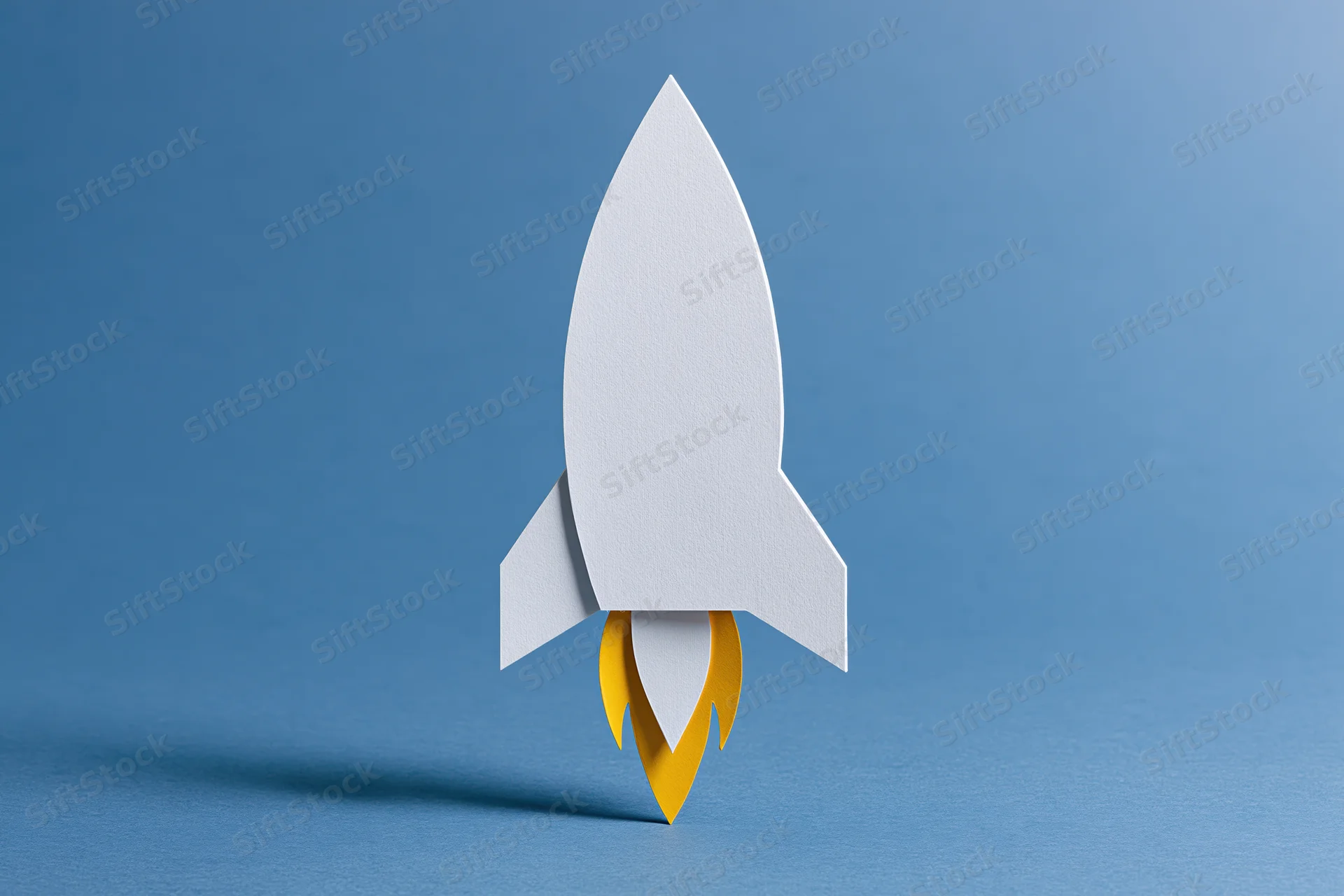 White paper-cut rocket with yellow flame cutout on blue background