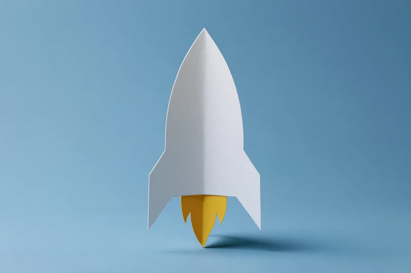 White paper rocket with yellow flame cutout on blue background