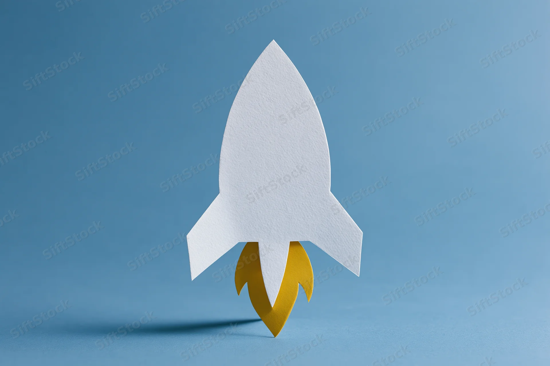 White paper-cut rocket with yellow flame cutout on blue background