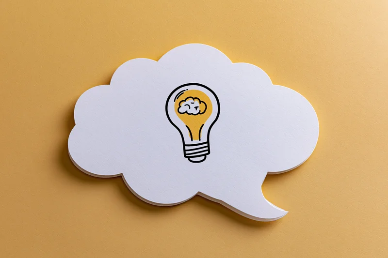 White paper thought bubble with hand-drawn lightbulb on yellow background