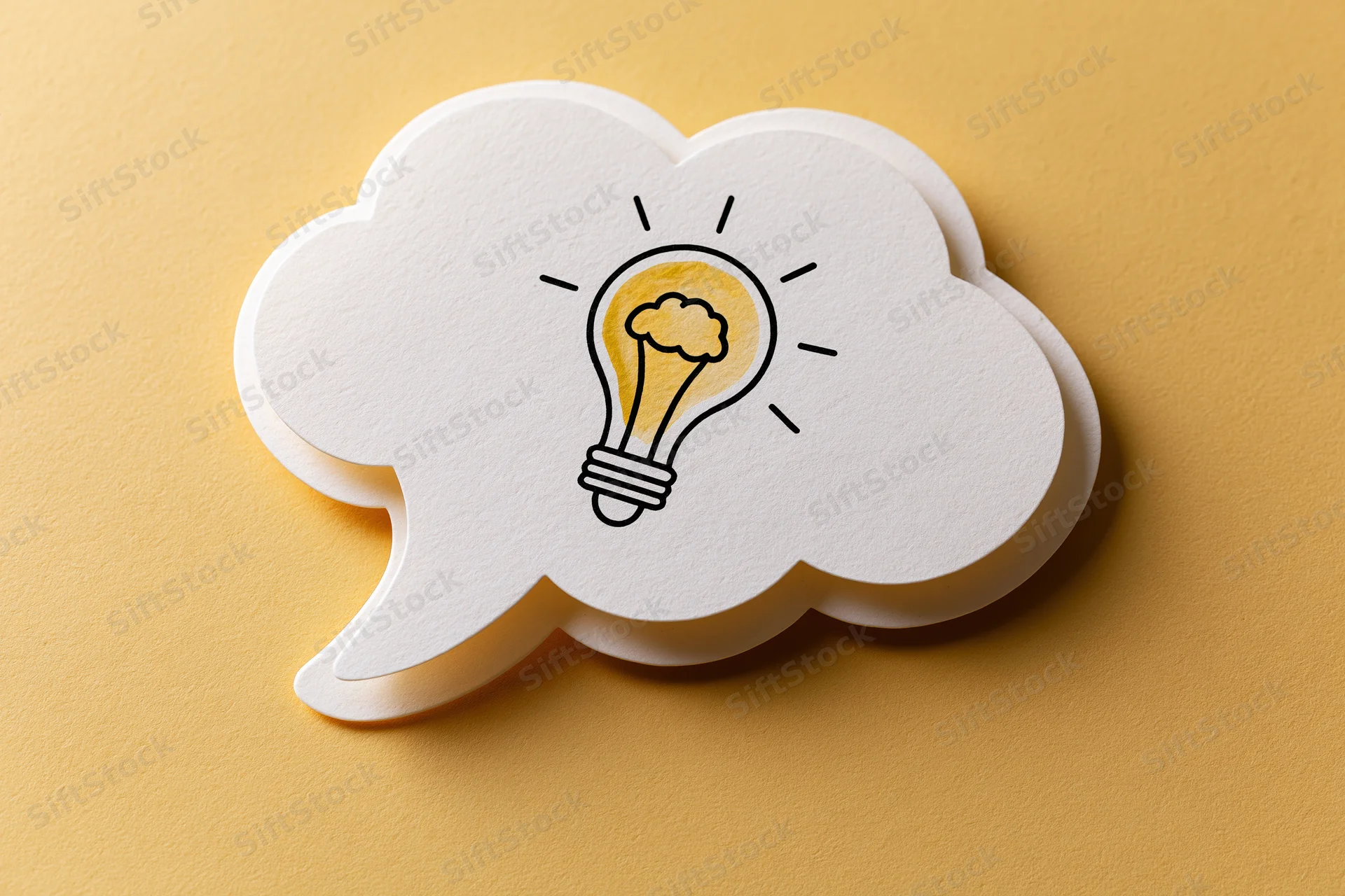 White paper thought bubble with hand-drawn lightbulb on yellow background