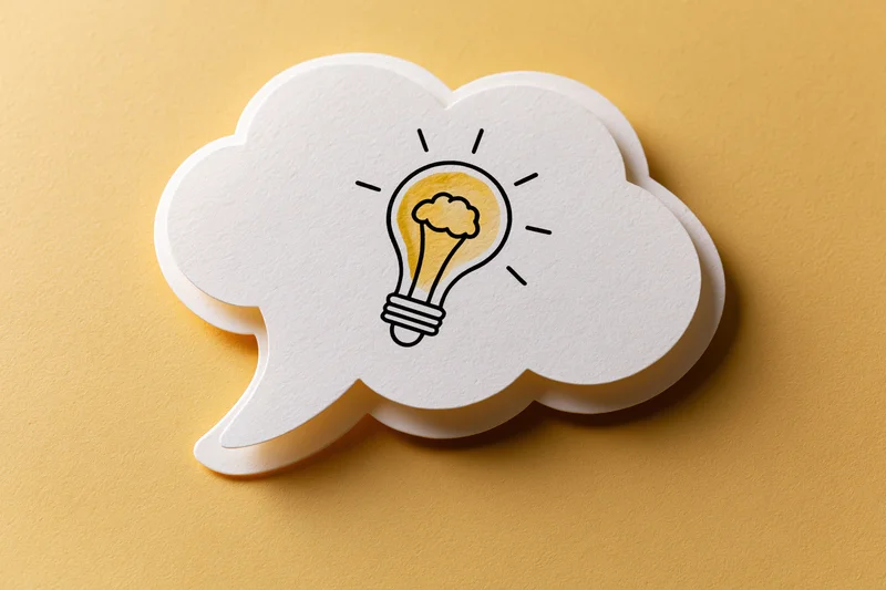 White paper thought bubble with hand-drawn lightbulb on yellow background