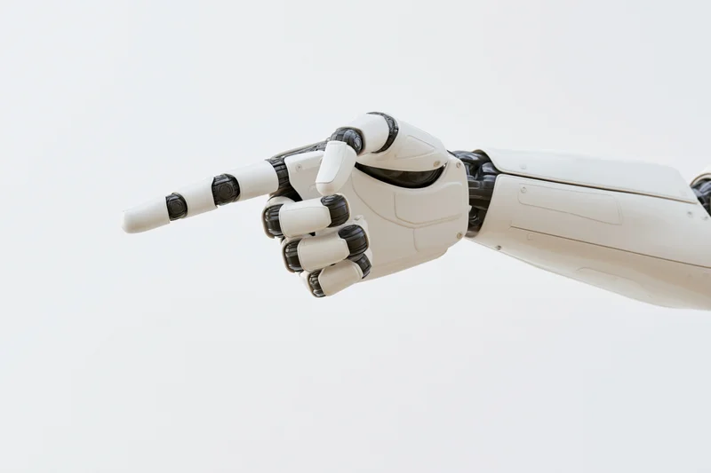 Robotic hand pointing forward against white background