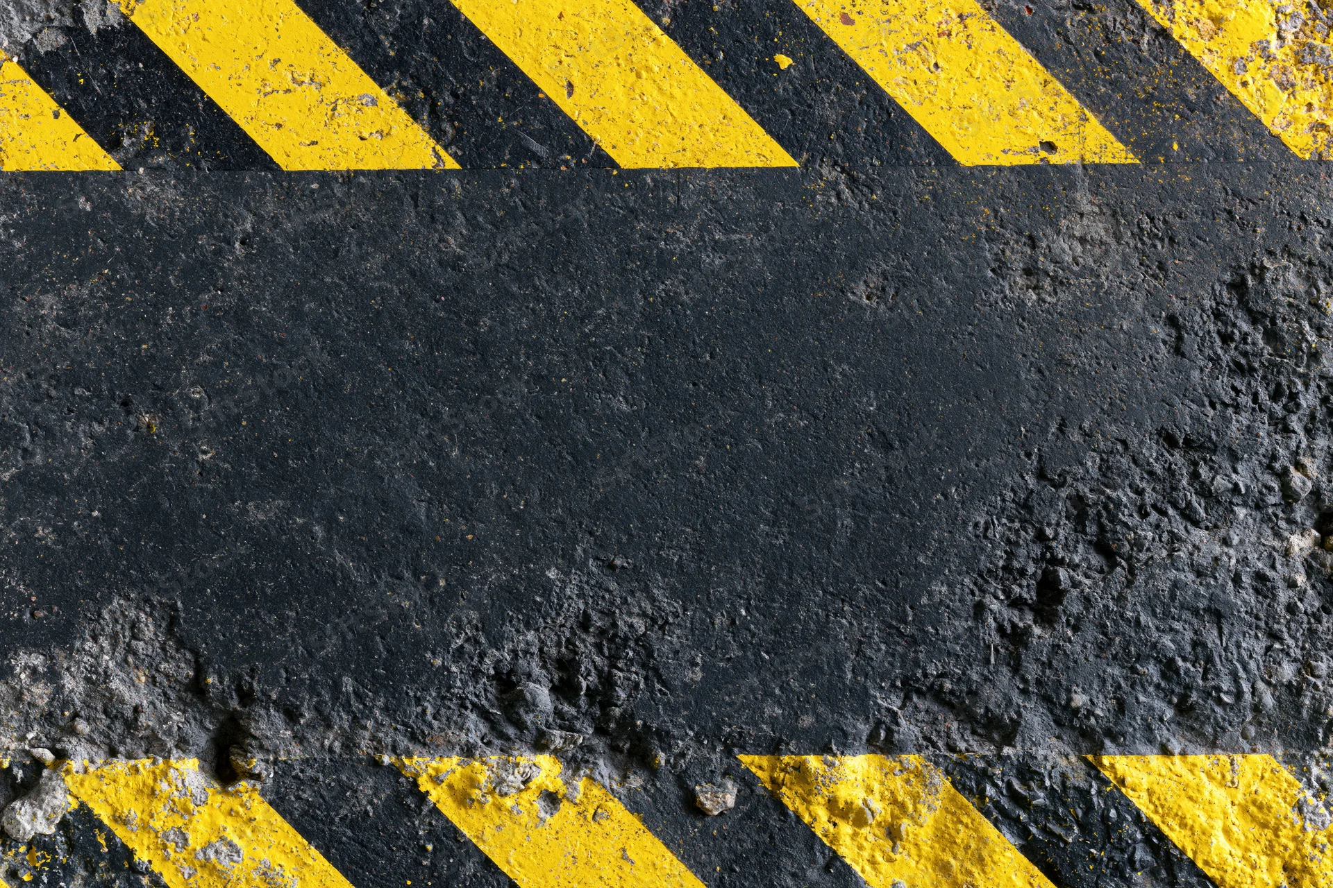 Worn industrial concrete surface with bold yellow and black diagonal hazard stripes
