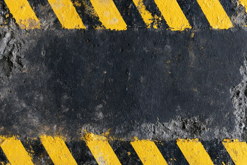 Worn industrial concrete surface with bold yellow and black hazard stripes