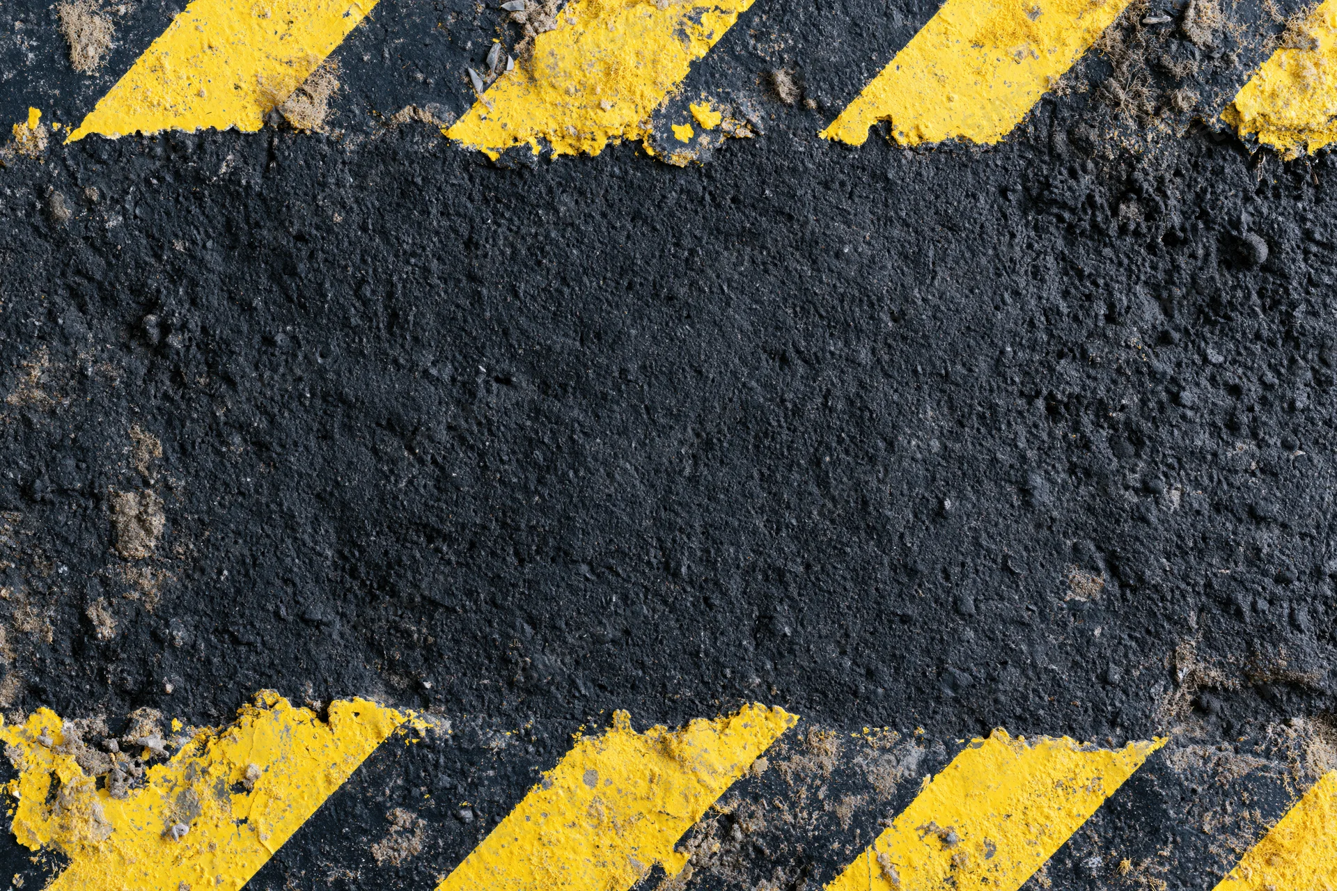 Worn industrial concrete surface with bold yellow and black diagonal hazard stripes