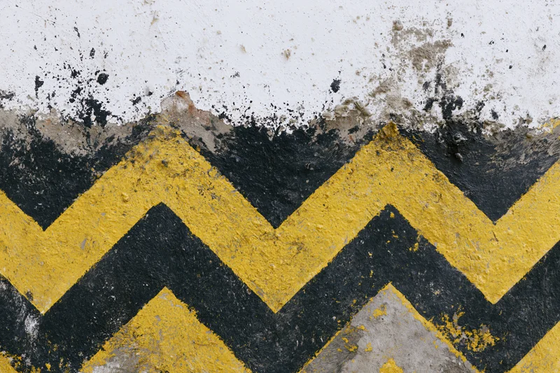 Worn yellow and black chevron stripes painted on a concrete surface