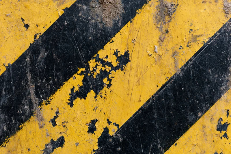 Worn yellow and black diagonal hazard stripes on a cracked concrete floor