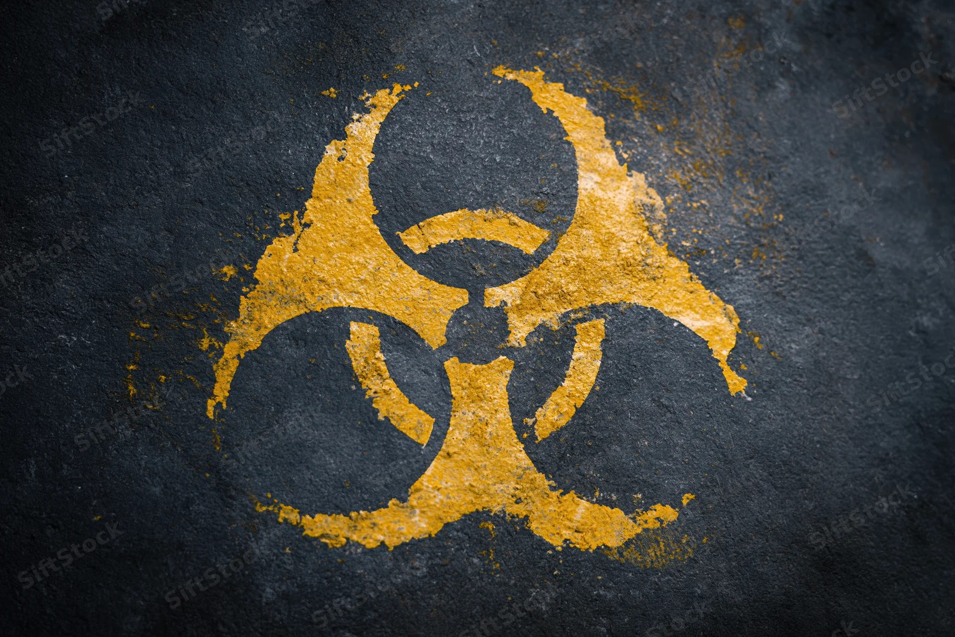 Yellow biohazard symbol painted on dark textured concrete surface