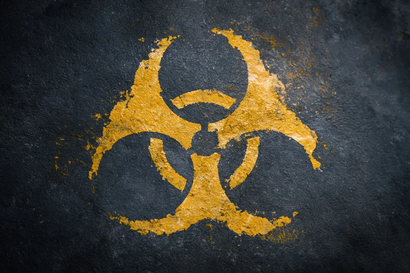 Yellow biohazard symbol painted on dark textured concrete surface