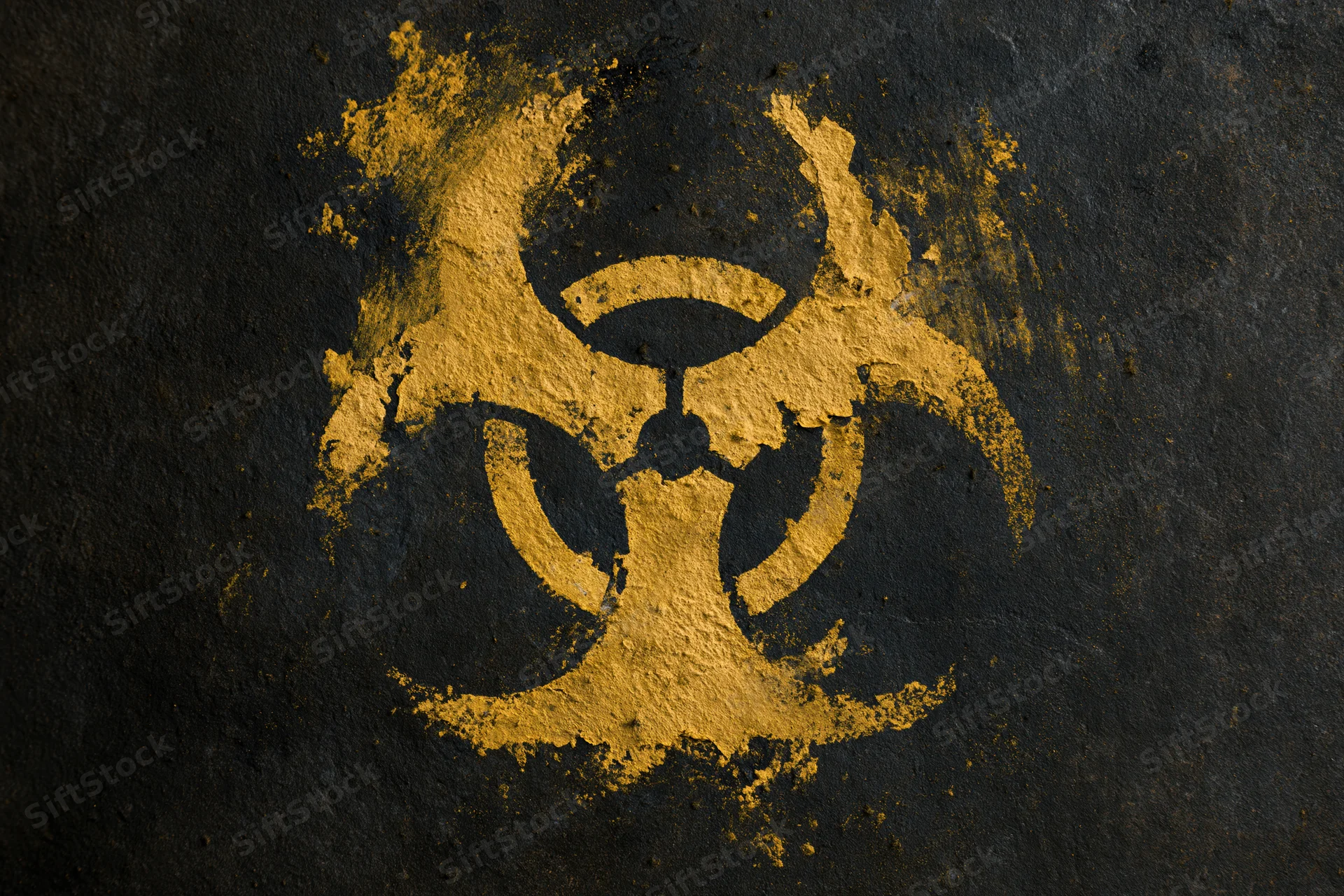 Yellow biohazard symbol painted on dark textured concrete wall