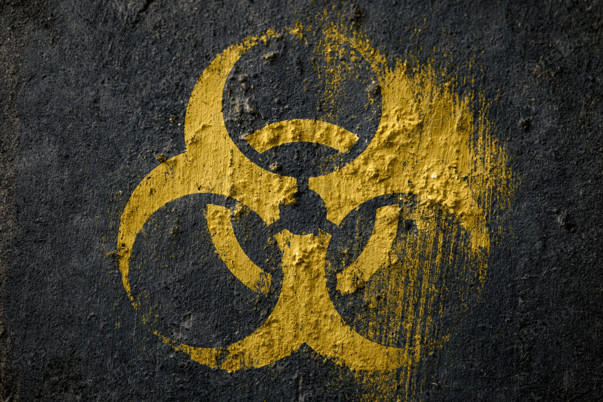 Yellow biohazard symbol painted on dark textured concrete surface
