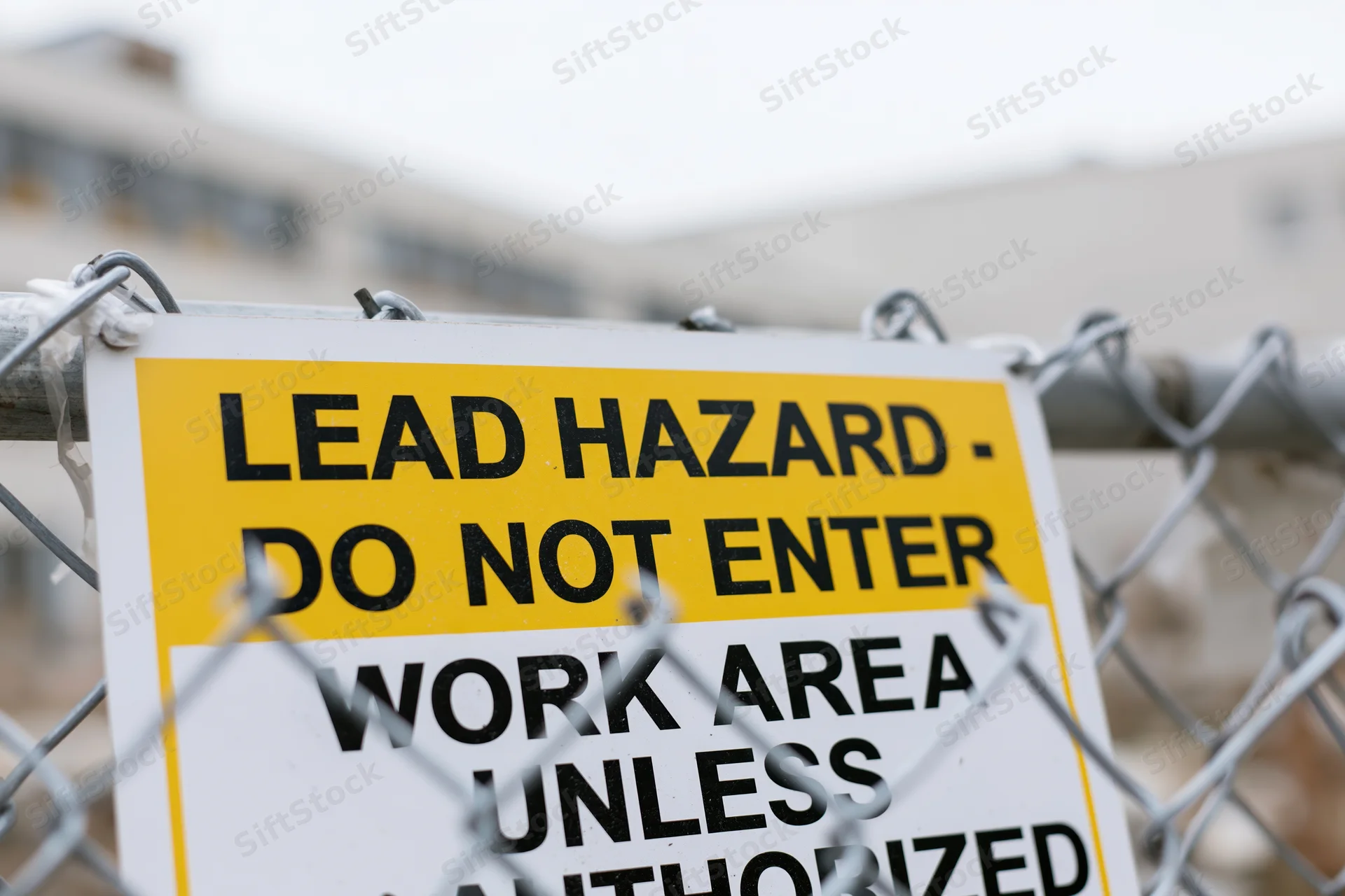 Lead hazard warning sign attached to chainlink fence at construction site