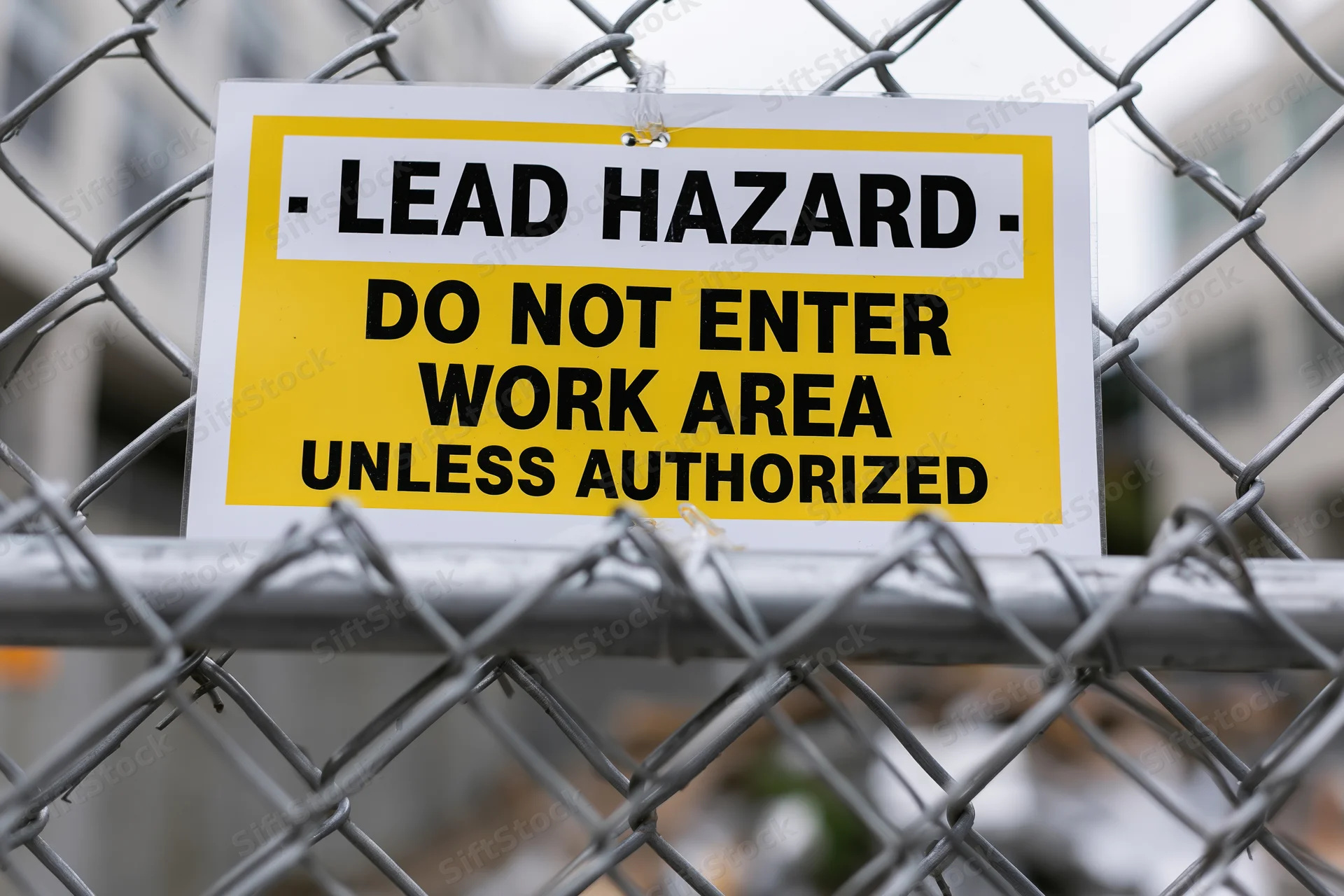 Lead hazard warning sign attached to chainlink fence at construction site