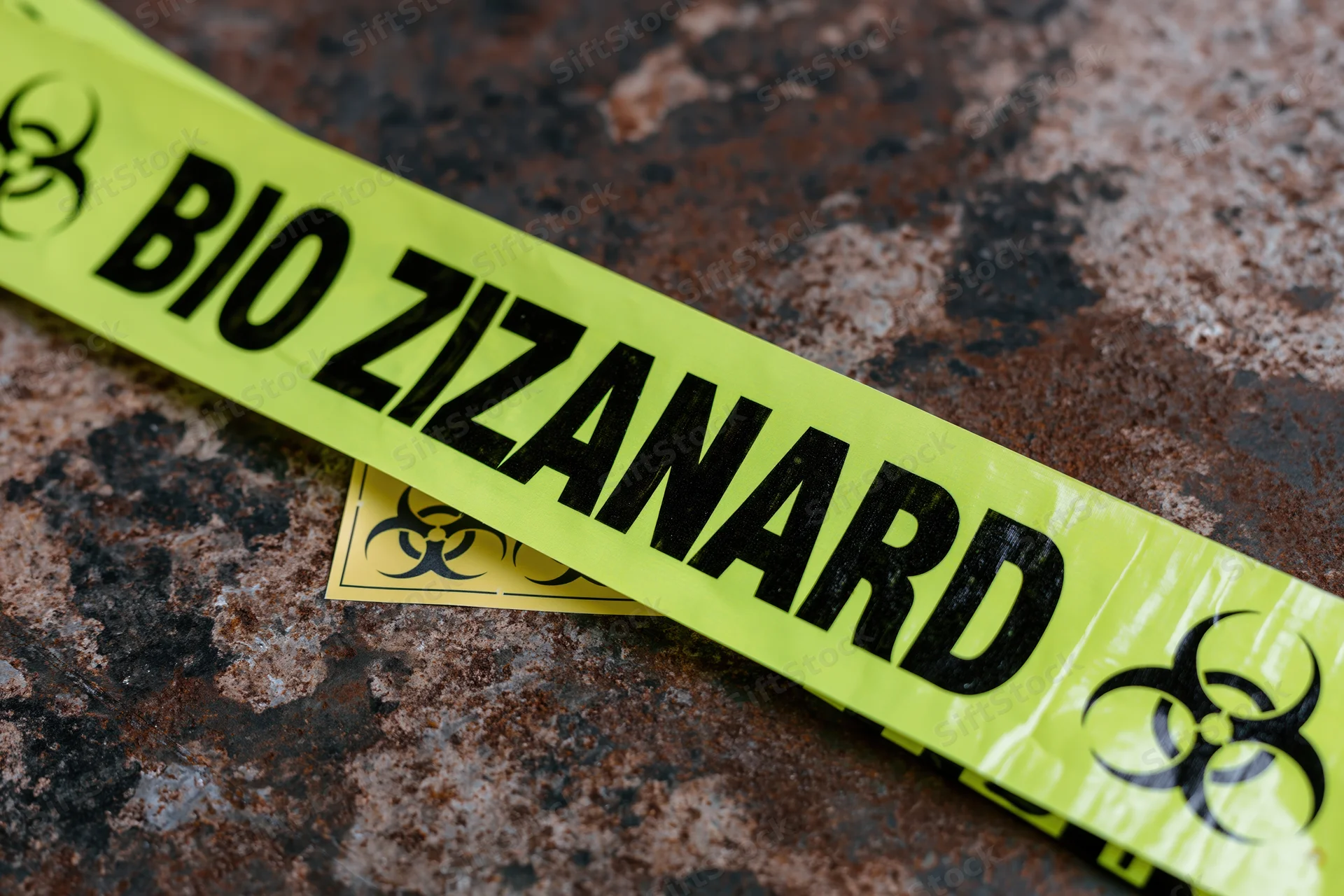 Yellow biohazard warning tape diagonally placed on a corroded metal surface