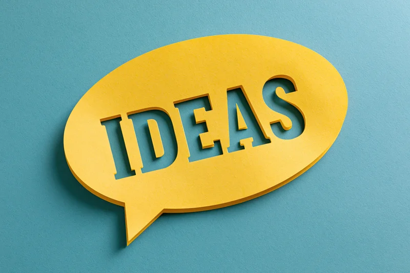 Yellow paper speech bubble with cutout word ideas on blue background