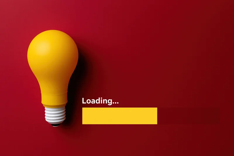 Yellow plastic lightbulb beside loading progress bar on red background