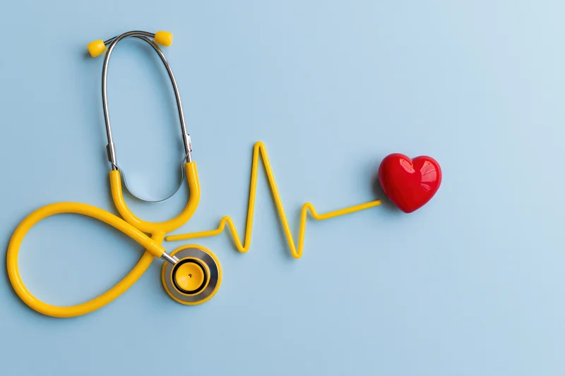 Yellow stethoscope with red heart and heartbeat line on blue background