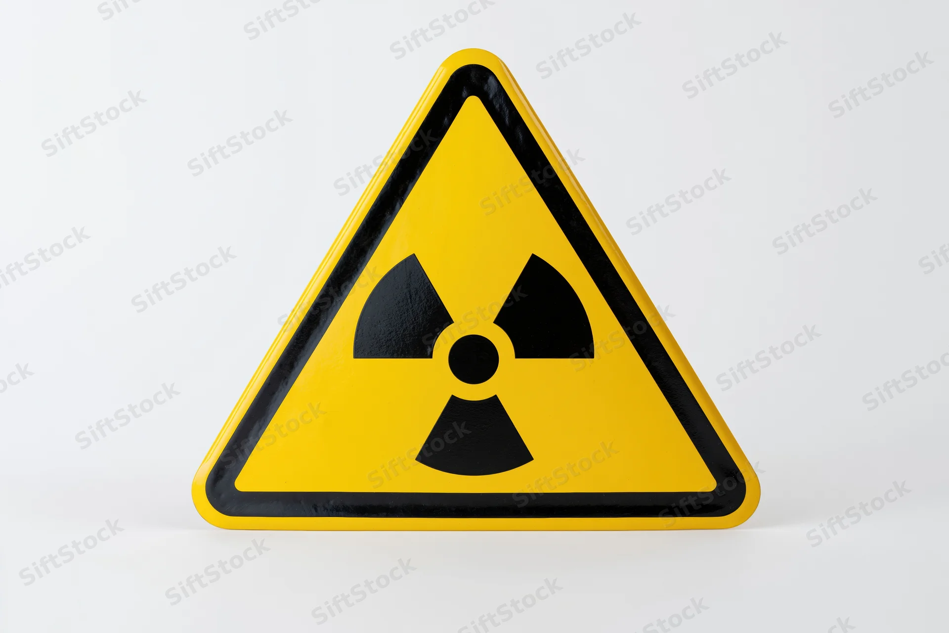 Yellow triangular radiation warning sign with black trefoil symbol on white background
