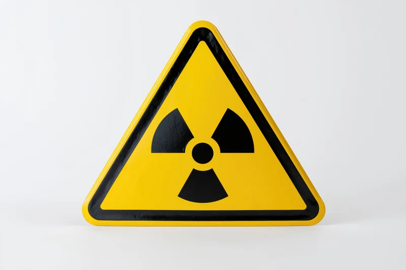 Yellow triangular radiation warning sign with black trefoil symbol on white background
